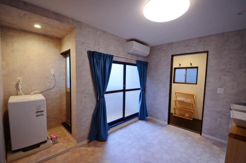 a bathroom with a shower and a window with blue curtains at Yamato Family House - 2 Floors | 3 bedrooms in Osaka