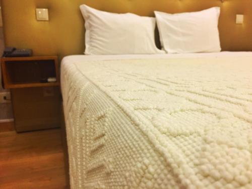 a bed with white sheets and pillows in a room at Hotel Estalagem Turismo in Bragança