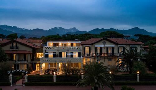 a large house with a mountain in the background at Hotel Byron in Forte dei Marmi