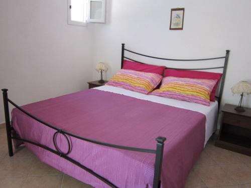 a bedroom with a large bed with purple sheets and pillows at Le Case dei Pescatori - Albicocco in Ponza