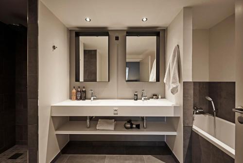 a bathroom with a white sink and two mirrors at Comwell Kongebrogaarden in Middelfart