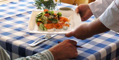 a person holding a plate of food on a table at Hotel zur Post in Kreuth
