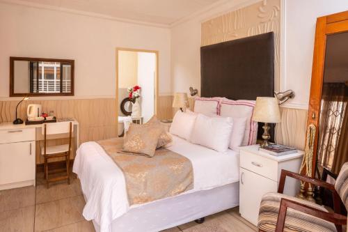 a bedroom with a white bed with a desk and a chair at SelaMod Village Guest House in Tshaneng