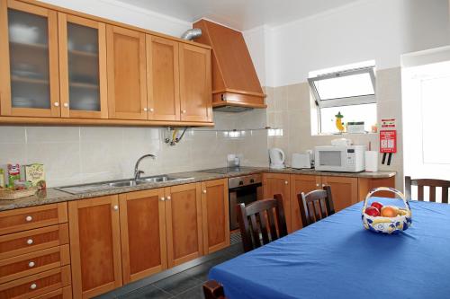 a kitchen with wooden cabinets and a table with a bowl of fruit at Casa Olhos de Mar - 7 min pé Praia in Peniche