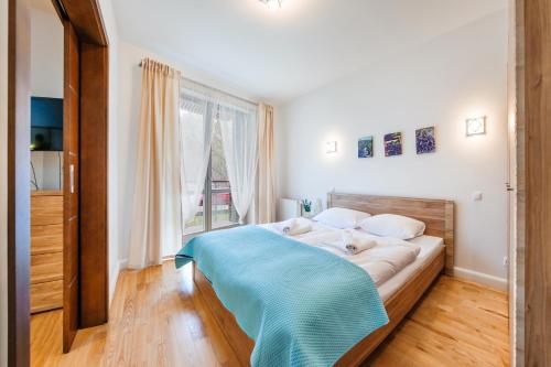 a bedroom with a large bed with a blue blanket at Apartamenty Sun & Snow Leśne Zacisze in Świnoujście