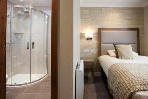 a bedroom with a shower and a bed and a tub at Cruachan Hotel in Fort William