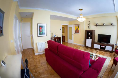 a living room with a red couch and a tv at Apartamentos Duque Ventas in Madrid
