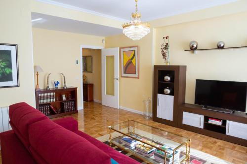 a living room with a red couch and a tv at Apartamentos Duque Ventas in Madrid