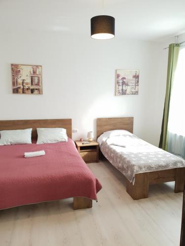 Un dormitorio con dos camas y una manta roja. en Green House, en Bucarest