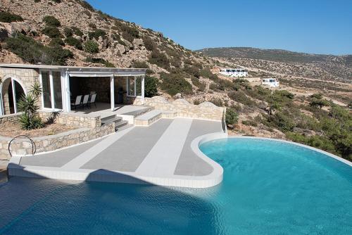 a house with a swimming pool next to a mountain at EVILIA LUXURY VILLA in Amoopi