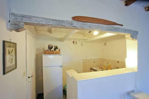 a kitchen with a white refrigerator and a wooden beam at Splendid cottage on Tuscan Sea in Porto Santo Stefano