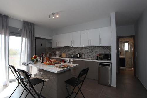 Una cocina con gabinetes blancos y una mesa y sillas. en Edem Beach Apartment with Sea View by Athenian Homes, en Atenas