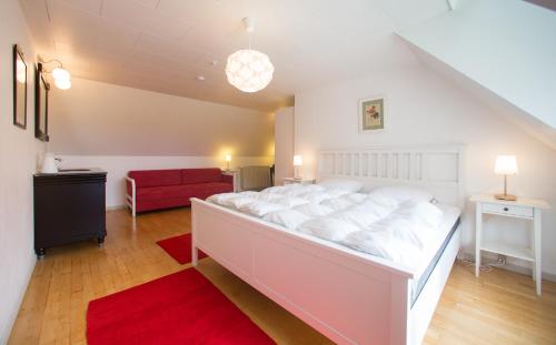 1 dormitorio con 1 cama blanca grande y 1 sofá rojo en Søndergård, en Borre