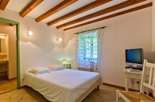 a bedroom with a bed and a desk and a television at AUBERGE DE LA MORENO in Saint-Genès-Champanelle