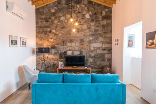 a blue couch in a living room with a stone wall at Azaleas Guest House in Ribeira Chã