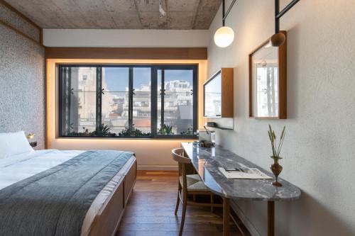 a bedroom with a bed and a desk and a window at Ergon House in Athens