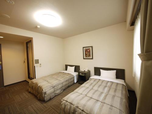 a hotel room with two beds and a window at Hotel Route-Inn Court Ina in Ina