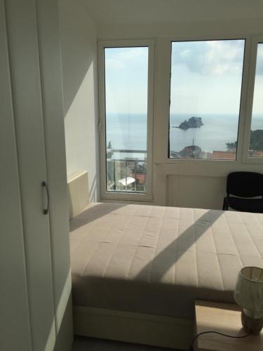 a bedroom with a bed and two windows at Oro Apartments in Petrovac na Moru