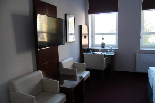 a hotel room with a television and a desk and chairs at Adena Hotel in Bremerhaven