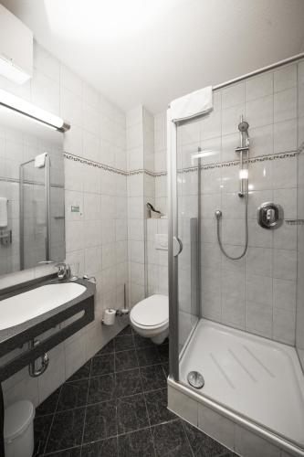 a bathroom with a shower and a toilet and a sink at Paulaner am Dom Hotel in Frankfurt/Main