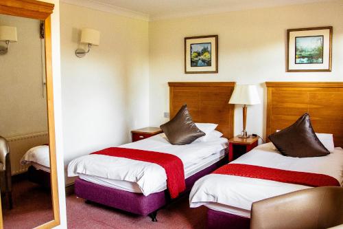 a hotel room with two beds and a mirror at Gatton Manor in Ockley