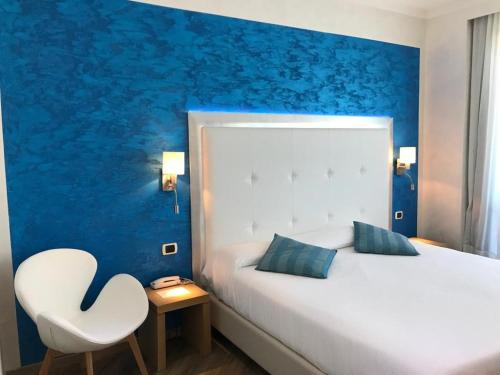 una camera con un letto bianco e una sedia bianca di Hotel Europa a Padova