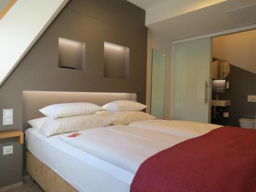 ウルムにあるホテルノイトアのベッドルーム1室(大型ベッド1台、白いシーツ、枕付)