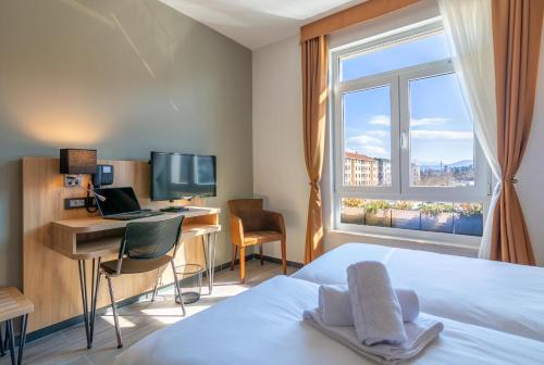 a bedroom with a bed and a desk with a computer at Hotel Resurs in Podgorica