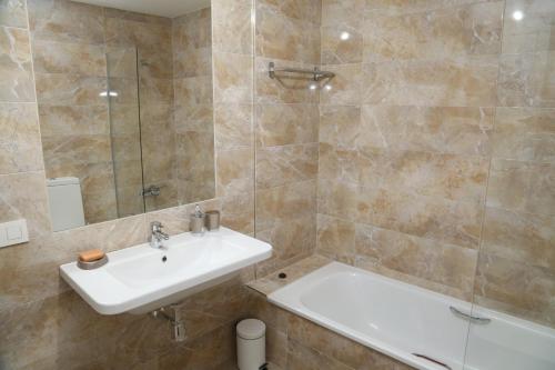 Apartamentos Turísticos Puente Romano P2 2-A في سلامنكا: حمام مع حوض ومرآة وحوض استحمام