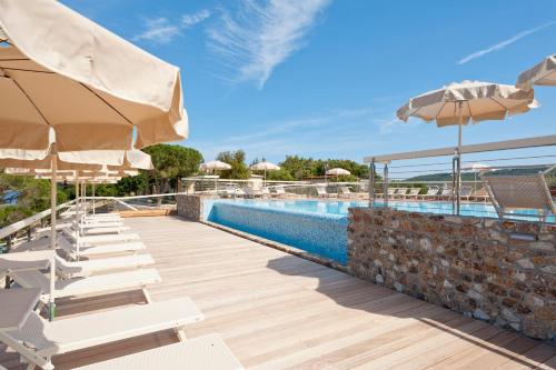 a swimming pool with lounge chairs and umbrellas at Hotel La Perla Del Golfo in Procchio