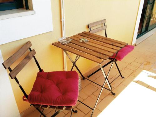 two chairs and a wooden table and a table and chairs at Apartamento Parque Ria Formosa, Olhão in Olhão