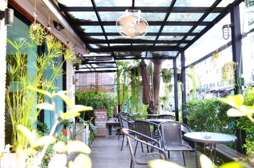 an outdoor patio with tables and chairs and plants at Early Bird Hostel Ayutthaya in Phra Nakhon Si Ayutthaya