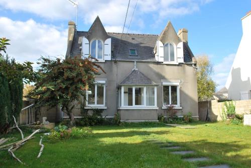 a house with a grass yard in front of it at Maison de village, charme scandinave in Carantec