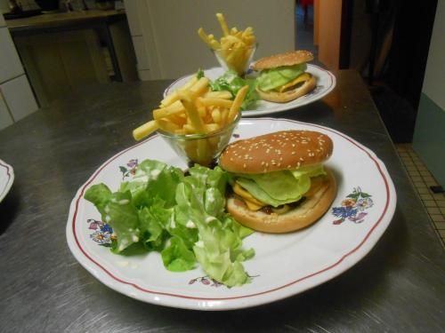 two plates of food with a hamburger and french fries at Le Logis du Pré Braheux in Saint-Nabord
