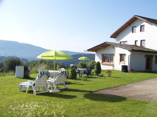 uma mesa e cadeiras com um guarda-sol num quintal em Gästehaus Rachelblick em Frauenau