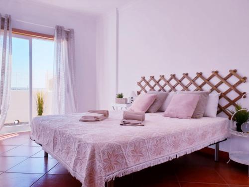 a white bedroom with a large bed with pink pillows at Quinta dos Arcos Feel At Home in Armação de Pêra