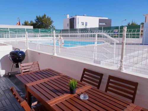 a wooden table and chairs on a balcony with a pool at Quinta dos Arcos Feel At Home in Armação de Pêra