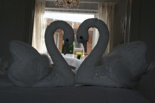 two swans dressed in white sitting on a bed at Country Dream - Langholt 2 in Selfoss