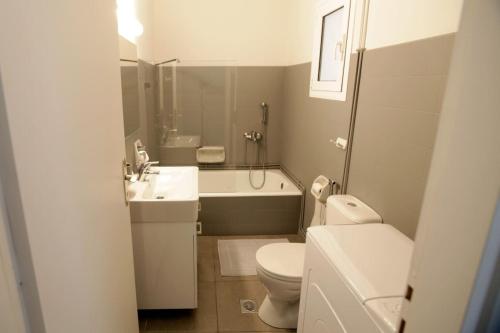 La salle de bains est pourvue de toilettes, d'un lavabo et d'une baignoire. dans l'établissement Seaside Renovated Top Floor Apartment, à Saronida