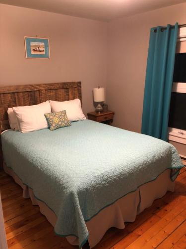 a bedroom with a large bed with blue curtains at Auberge d'Anjou-Sūrya Café in Petit Rocher