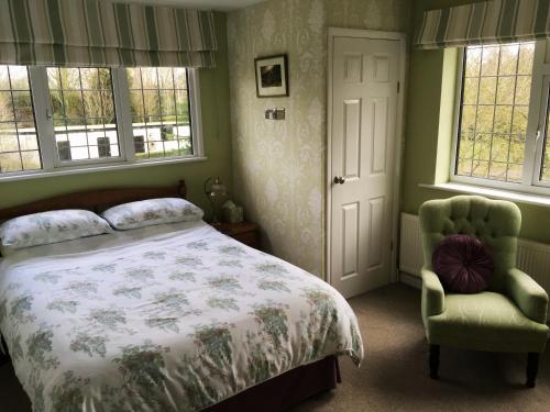 a bedroom with a bed and a chair and windows at The Beeches Bed and Breakfast in Hinckley