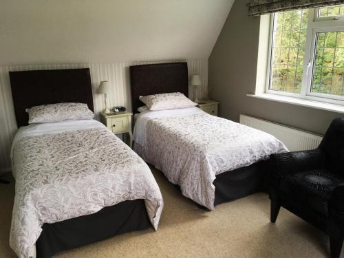 
two beds in a room with two windows at The Beeches Bed and Breakfast in Hinckley
