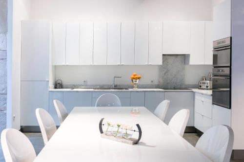 cocina blanca con mesa blanca y sillas blancas en La Maison Blanche en Beaune