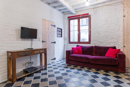 a living room with a purple couch and a tv at Romantic 16th century workers house in Ghent