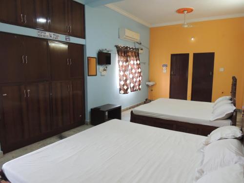 a hotel room with two beds and a tv at Radha Party Hall in Kanchipuram