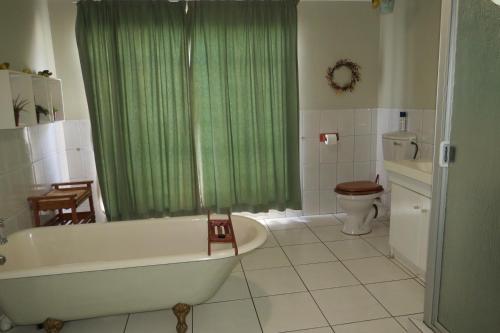 a bathroom with a tub and a green shower curtain at Lajava Guest Lodge in Krugersdorp