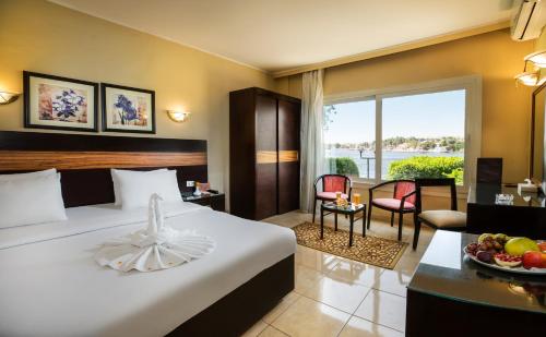 una camera d'albergo con letto e tavolo con piatto di frutta di Obelisk Nile Hotel Aswan a Aswan