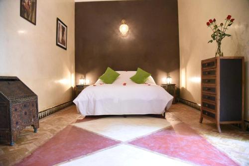 a bedroom with a white bed with green pillows and a dresser at Tigmi Nomade in Tahannout