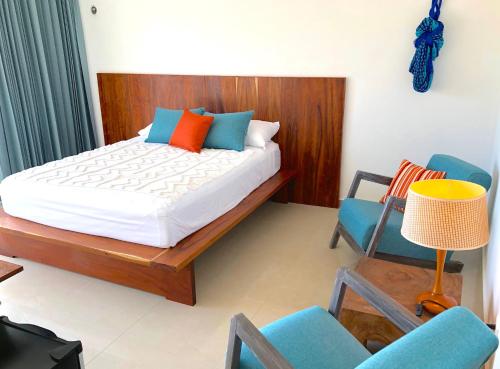 a bedroom with a bed and two chairs and a lamp at Playa 55 beach escape - adults only Guesthouse in Celestún