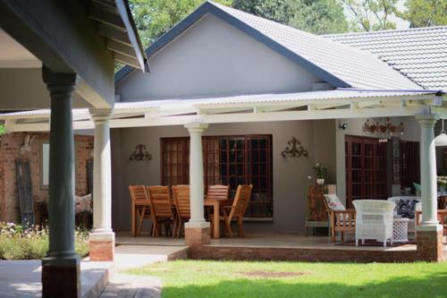 a house with a porch with a table and chairs at Dancing River Guesthouse in Vereeniging
